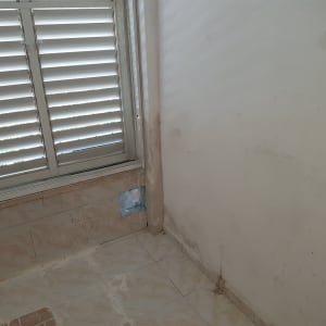 קיר עם סימני צבע ותיקונים ליד חלון