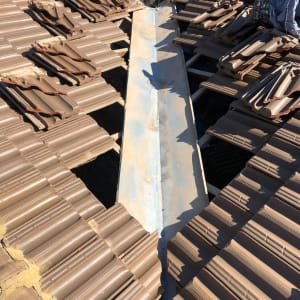 רעפים חומים מונחים על גג עם תעלה מתכתית במרכז