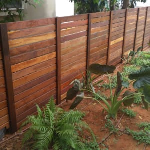 גדר עץ חומה עם צמחים ירוקים בגינה