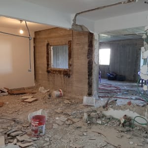 אתר בנייה עם קירות שבורים, דליים וחוטי חשמל חשופים