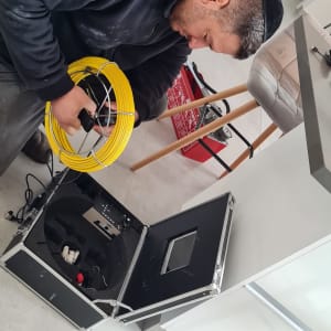 אדם מחזיק כבל צהוב ליד מזוודה פתוחה עם ציוד אלקטרוני