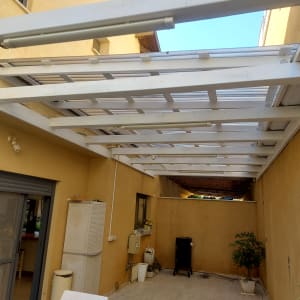 פרגולה מעץ לבן בחצר עם צמחים ועציצים