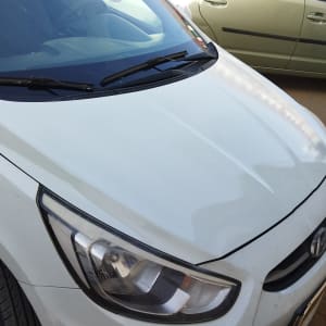 מכונית לבנה עם פנס קדמי וחלקי גוף נראים