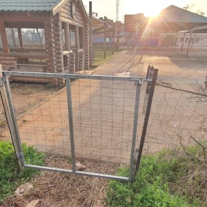 שער מתכת עם רשת ליד מבנה עץ