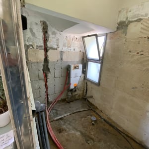 קירות חשופים עם צינורות אדומים ושחורים, חלון פתוח