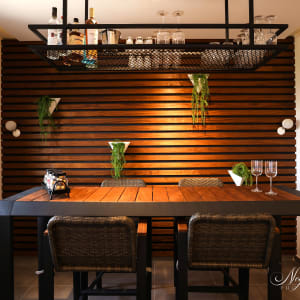 שולחן עץ עם כיסאות, מדף עם בקבוקים וכוסות