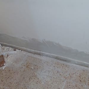 קיר צבוע חלקית עם סימני טיח על הרצפה