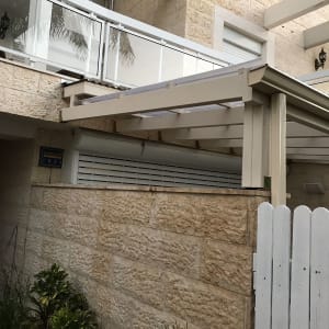 גדר עץ לבנה ליד קיר אבן וצמחייה