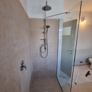 מקלחת חדשה עם אריחים, ראש מקלחת ודלת זכוכית