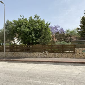 גדר עץ חומה על קיר אבן בגינה