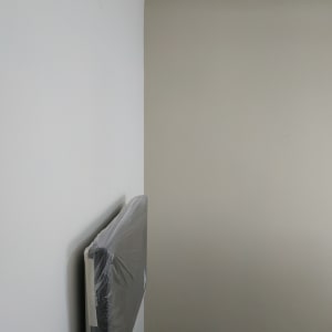 קיר צבוע בשני גוונים עם רדיאטור מכוסה בניילון