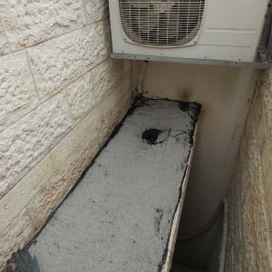 איטום גג עם חומר שחור ליד מזגן