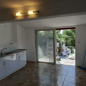 מטבח עם ארונות לבנים ודלת זכוכית לחצר