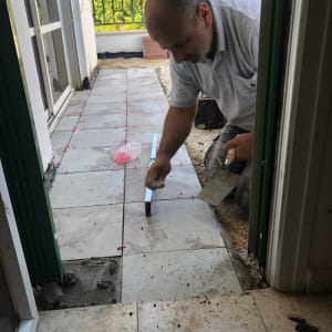 אדם מתקין אריחים על רצפה עם כלי עבודה