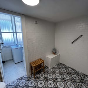 חדר רחצה עם אריחים מעוצבים, ספסל עץ וקיר לבנים