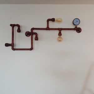 צינורות מתכת עם נורות ומד לחץ על קיר