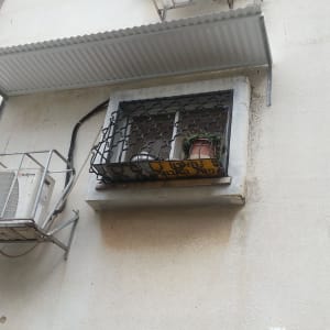 סורגי אלומיניום על חלון עם מזגן חיצוני