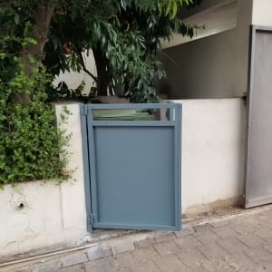 שער מתכת כחול פתוח ליד קיר לבן