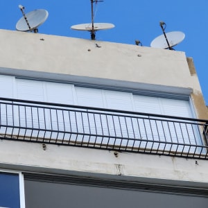 מעקה מתכת שחור על מרפסת עם תריסים לבנים