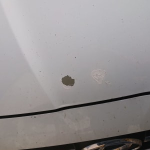 נזקי פחחות על מכסה מנוע של רכב לבן