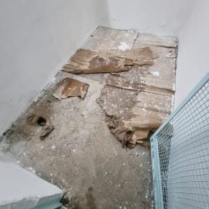 רצפה עם קרטון קרוע וכתמי צבע לבן