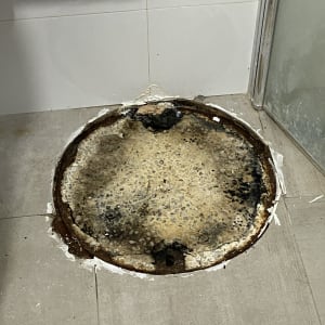 פתח ביוב עגול עם סימני חלודה על הרצפה