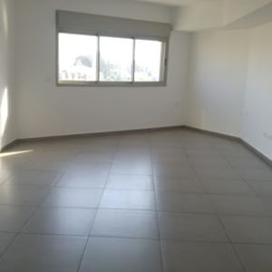 חדר ריק עם רצפת אריחים נקייה וחלונות גדולים