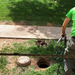 אדם מחזיק צינור ליד פתח ביוב פתוח