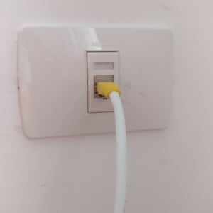כבל רשת צהוב מחובר לשקע קיר לבן