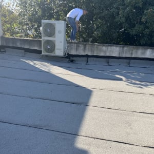 אדם על גג עם יריעות איטום ואיטום סביב מזגן