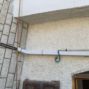 צינור פלסטיק לבן מחובר לקיר עם כבל ירוק