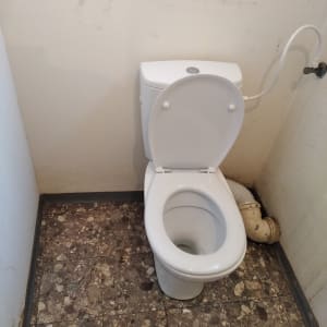 אסלה עם צינור ניקוז לבן מחובר לקיר