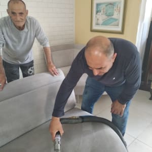 ניקוי ספה עם שואב אבק על ידי אדם