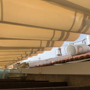 סוכך בד צהוב עם קפלים מעל גג רעפים