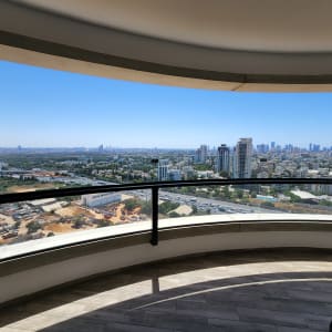 מעקה זכוכית מעוגל במרפסת עם נוף עירוני