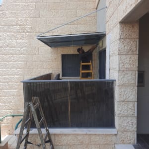 אדם מתקין סוכך מתכת על מרפסת עם סולם