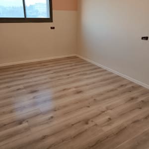 רצפת פרקט עץ בהירה בחדר ריק עם קירות בהירים