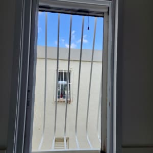 חלון עם סורגים לבנים מול קיר חיצוני