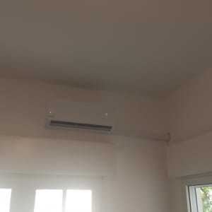 מזגן מותקן על קיר לבן עם תצוגה דולקת