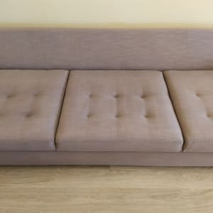 ספה חומה עם שלושה מושבים על רצפת עץ