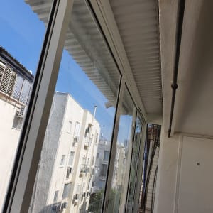 חלונות אלומיניום במרפסת סגורה עם נוף לבניינים