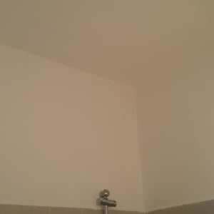 קיר צבוע בלבן עם מסגרת חלון אפורה