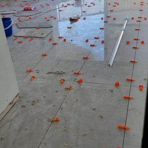 ריצוף חדש עם חוצצים כתומים, דליים וכלי עבודה