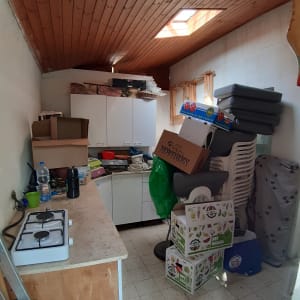 חדר אחסון עם קופסאות, כיסאות ומכשירי מטבח