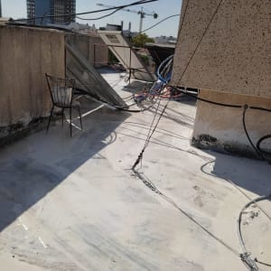 גג עם חומר איטום לבן, כבלים וצלחות שמש