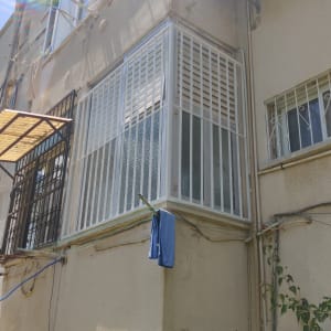 מסגרת מתכת סביב מרפסת סגורה עם תריסים