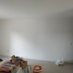 קיר צבוע בלבן עם כלים לצביעה על הרצפה