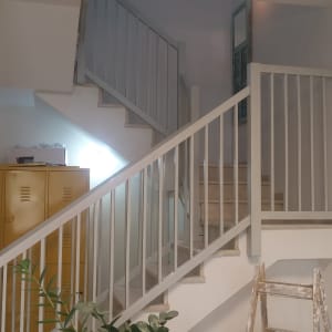 סולם עץ צבוע ליד מעקה מדרגות לבן