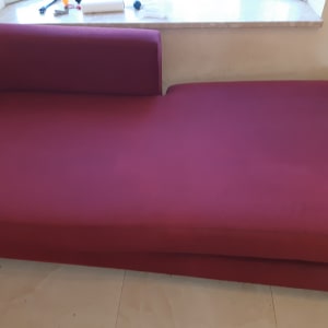 ספה אדומה עם כלים לניקוי על אדן החלון