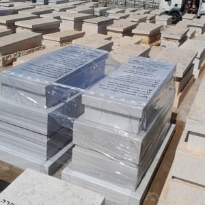 Gravestones in a cemetery, some wrapped in plastic.
